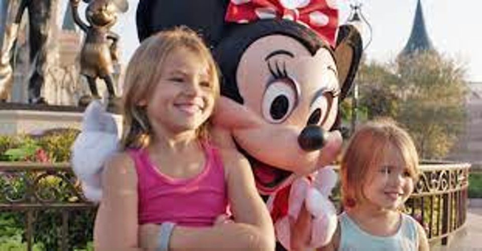 While posing for a picture with Minnie Mouse, these two sisters keep a close check on Minnie’s hand.