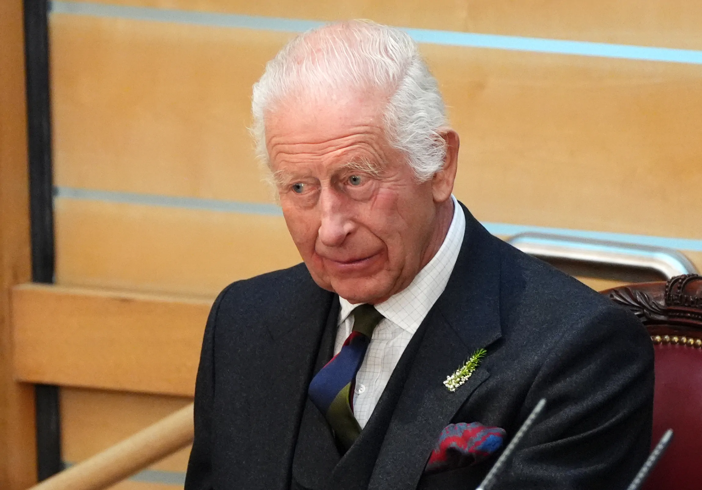 King Charles sits in a chair in the Scottish Parliament